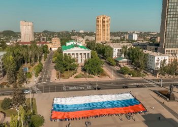 Флаг России, развёрнутый в 5 городах ДНР, уезжает в Москву на церемонию